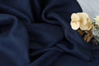 a close-up view of a dark blue fabric with a delicate white flower resting on top of it.