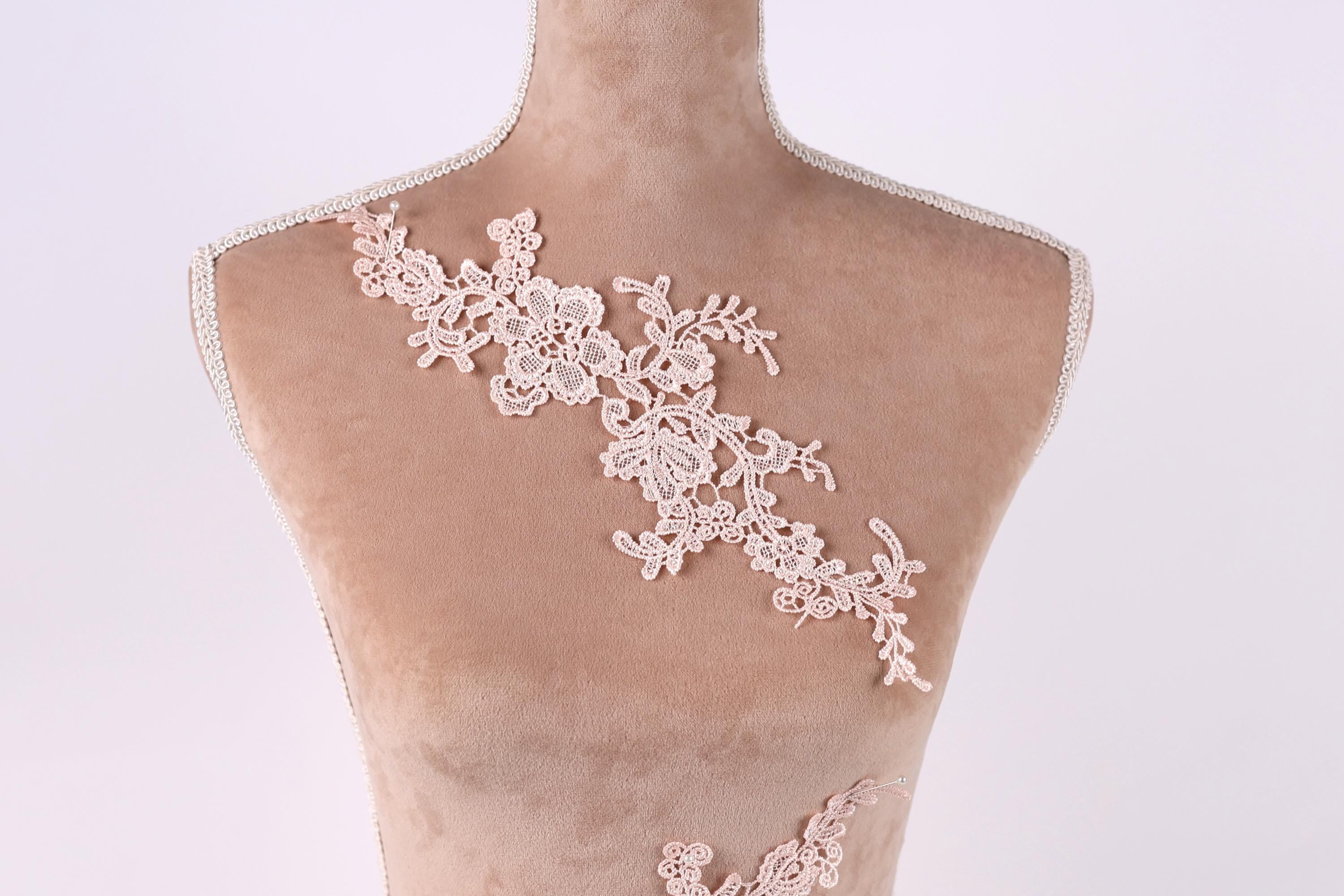 A mannequin with a delicate, lace-like floral pattern on its bust area.