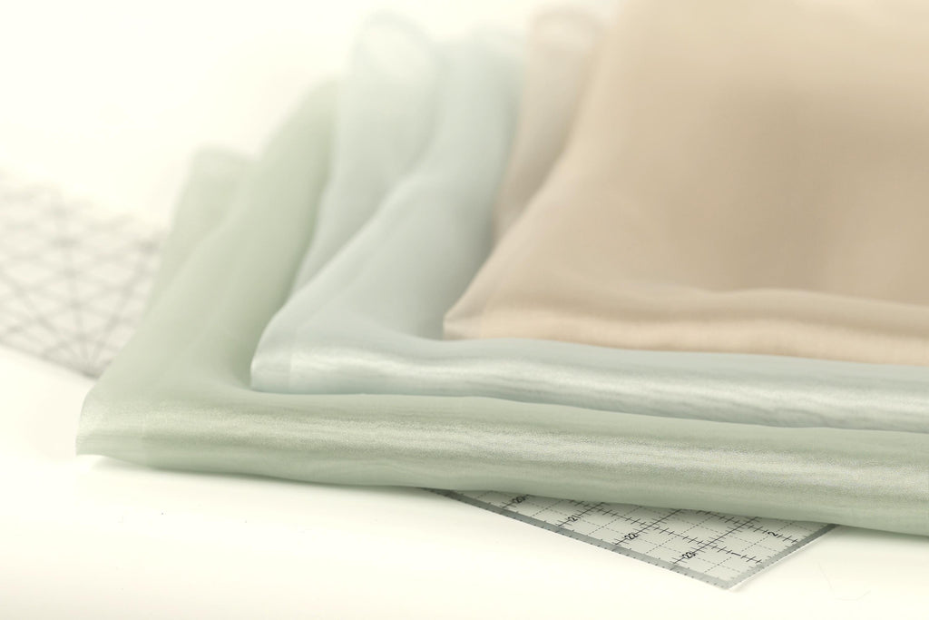 a close-up view of a stack of fabric swatches, with a clear ruler placed on top of them.