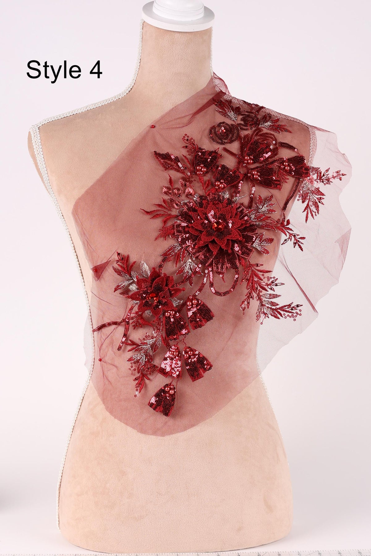 A mannequin wearing a red floral embellishment on its shoulder.