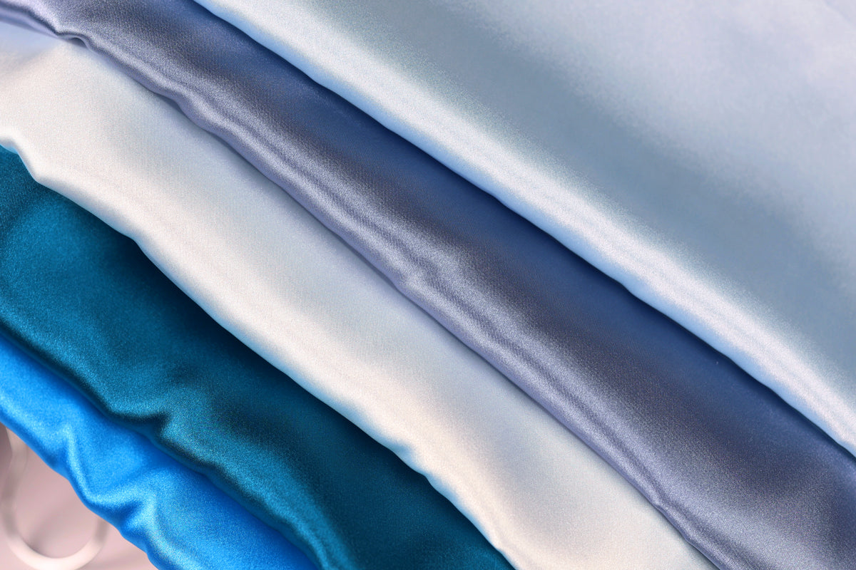 a close-up view of several pieces of blue, white, and gray satin fabric, arranged in a diagonal line.