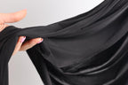 A hand holding a black fabric, with the fingers curled around it.