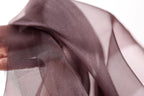 A close-up view of a piece of brown fabric, possibly silk or chiffon, with a blurred background.