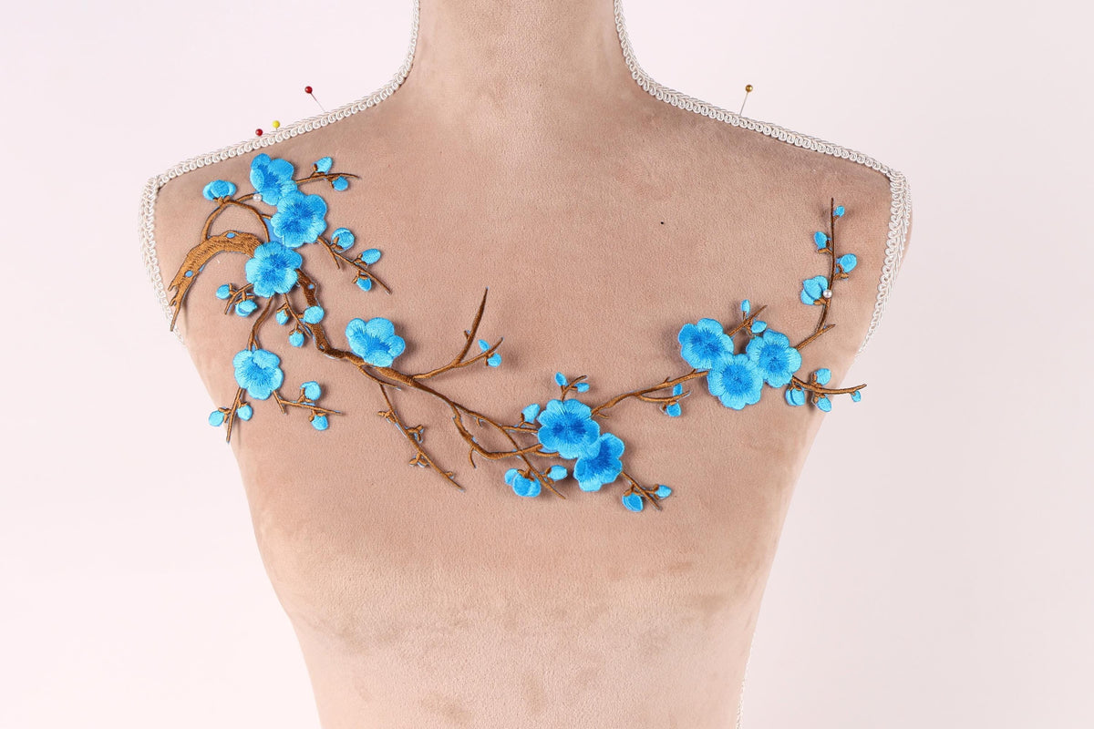 A mannequin bust with a floral design on the shoulder area, featuring blue flowers and branches.