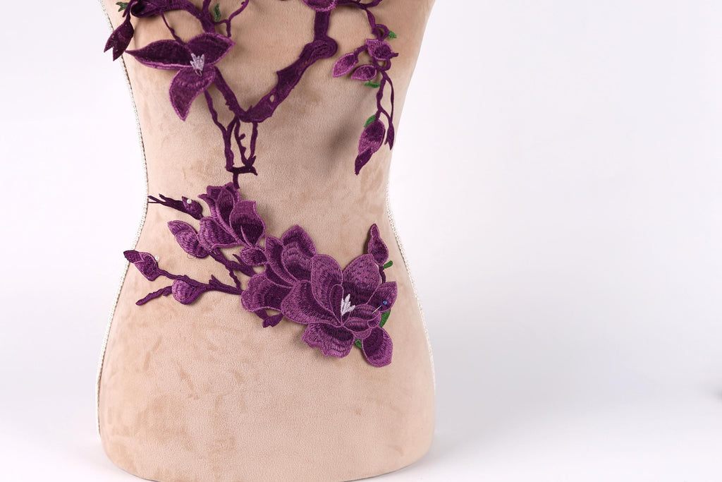 A mannequin torso with purple floral embroidery on it.