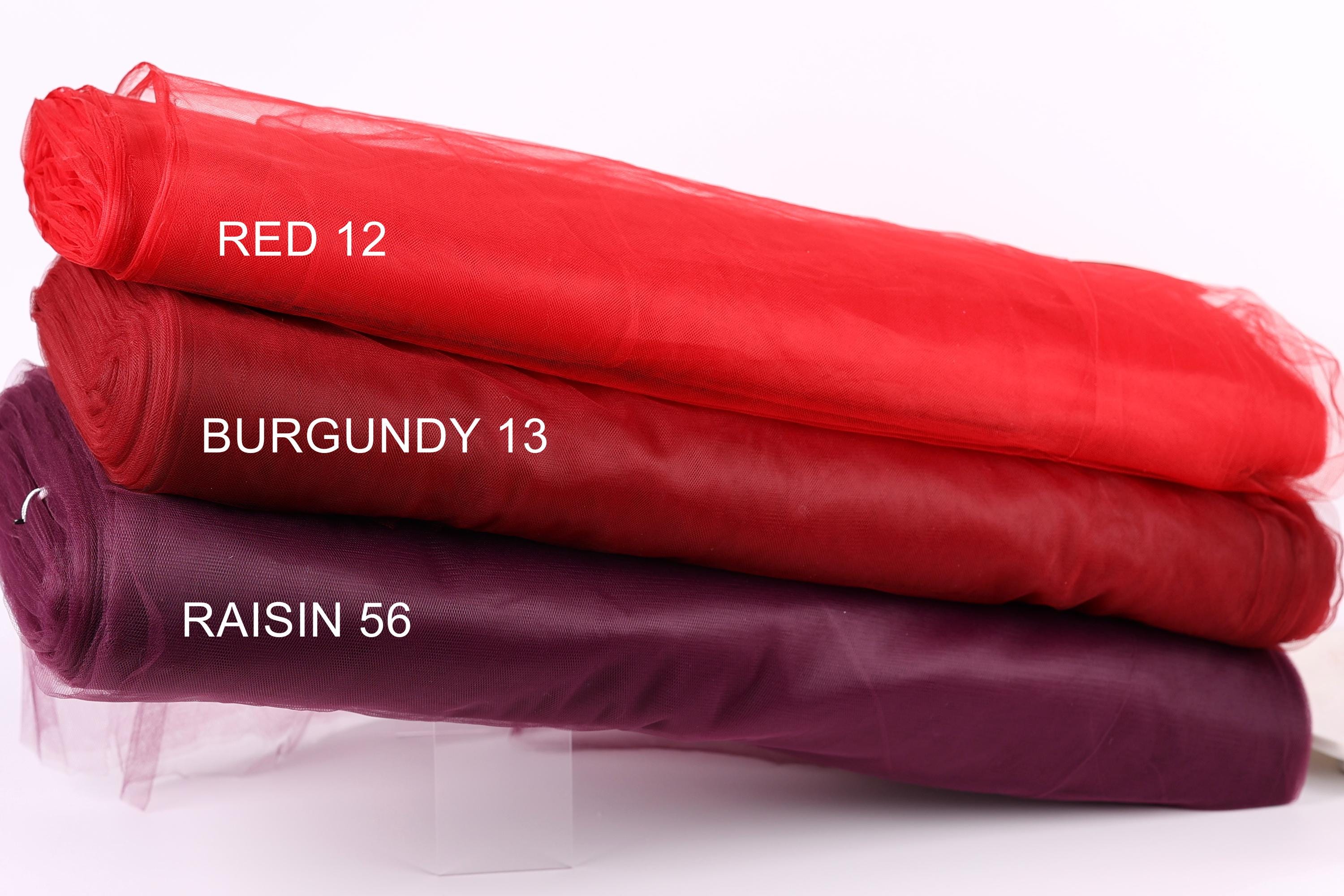 three different colored tulle fabric rolls, each labeled with a color name: red, burgundy, and raisin.