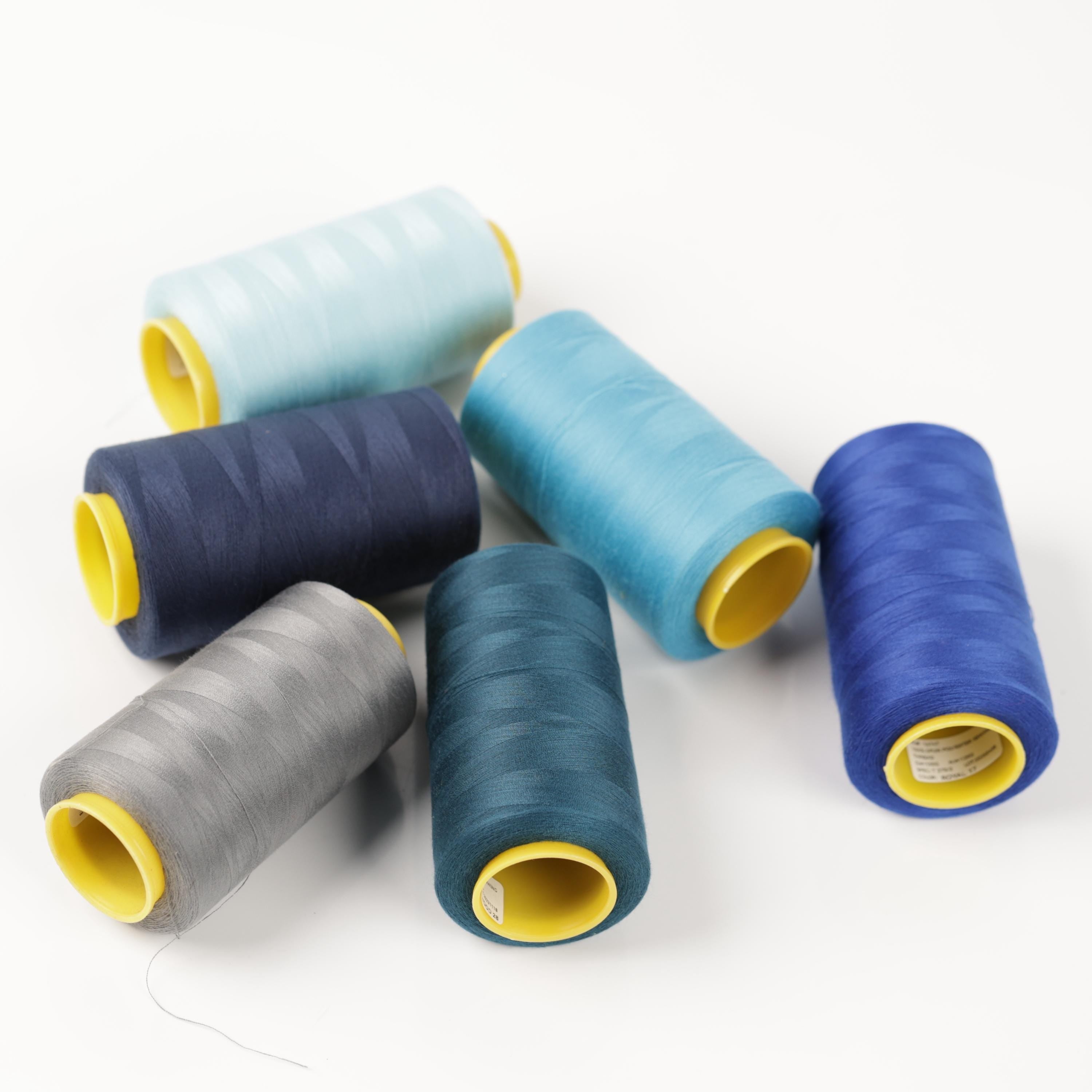 a collection of six spools of thread in various colors, including blue, gray, and yellow, arranged on a white background.