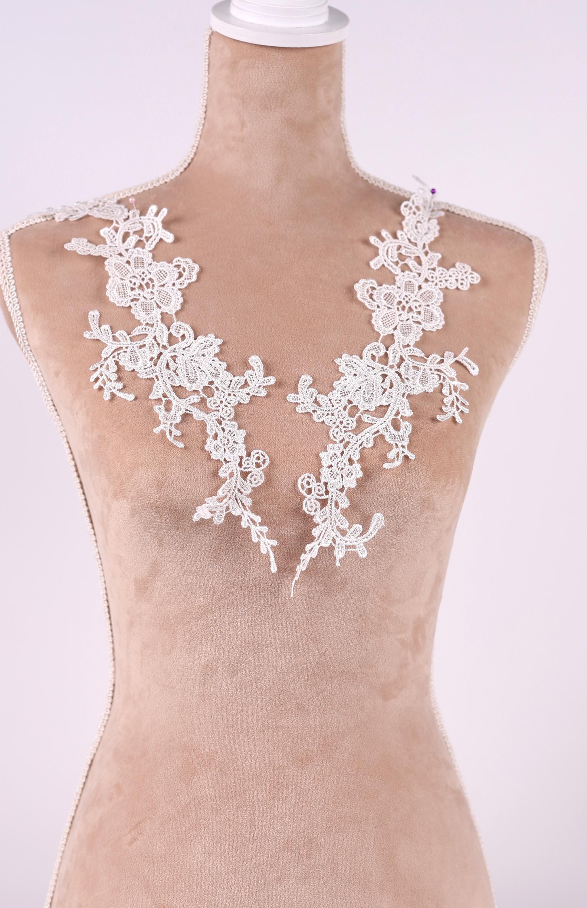 A mannequin wearing a dress with delicate white lace details on the neckline.