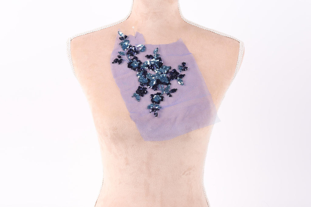 a mannequin torso with a piece of fabric or material attached to it, featuring a floral pattern in shades of blue and purple.