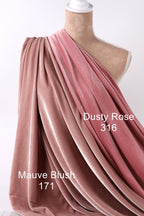 a mannequin wearing a draped fabric in shades of pink and red, with the fabric appearing to be made of velvet. The fabric is draped over the mannequin's shoulder, creating a flowing and elegant appearance.