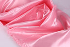 A close-up view of a soft, shiny pink satin fabric, with a smooth and flowing texture.