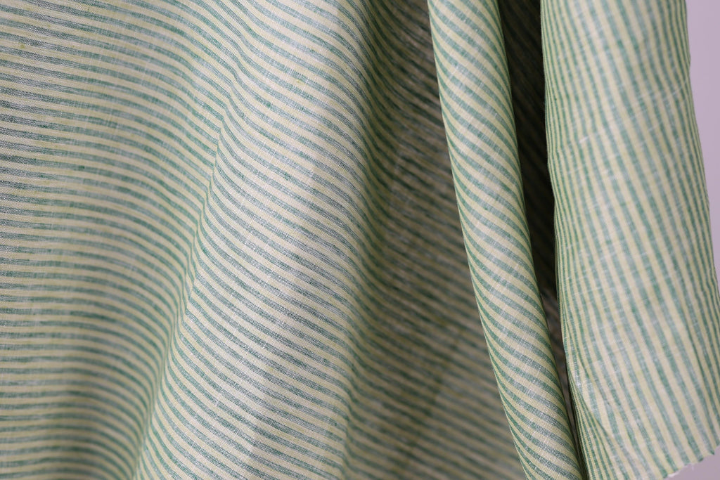 A close-up view of a fabric with green and white striped patterns, creating a textured and visually interesting surface.