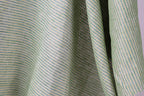 A close-up view of a fabric with green and white striped patterns, creating a textured and visually interesting surface.
