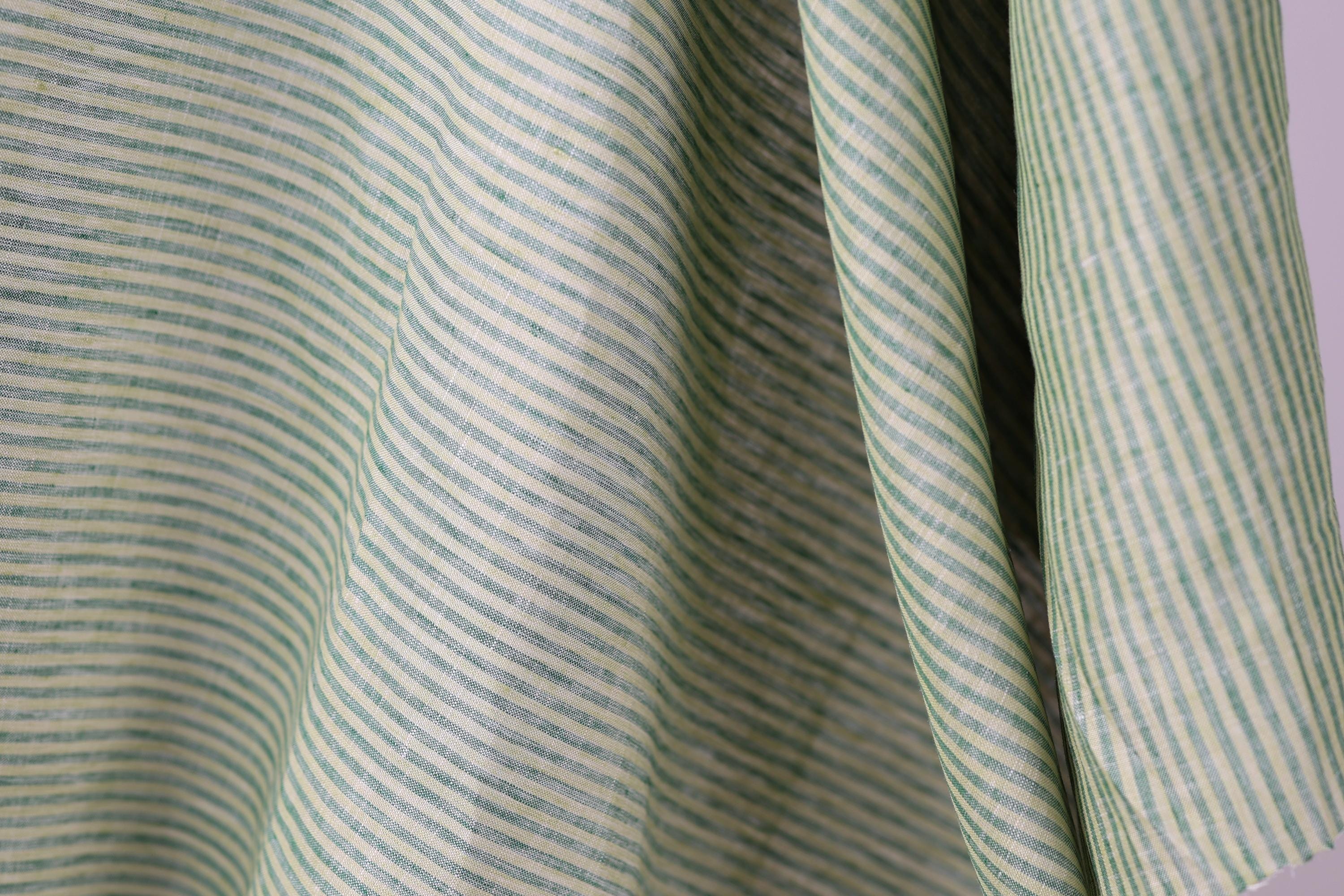 A close-up view of a fabric with green and white striped patterns, creating a textured and visually interesting surface.