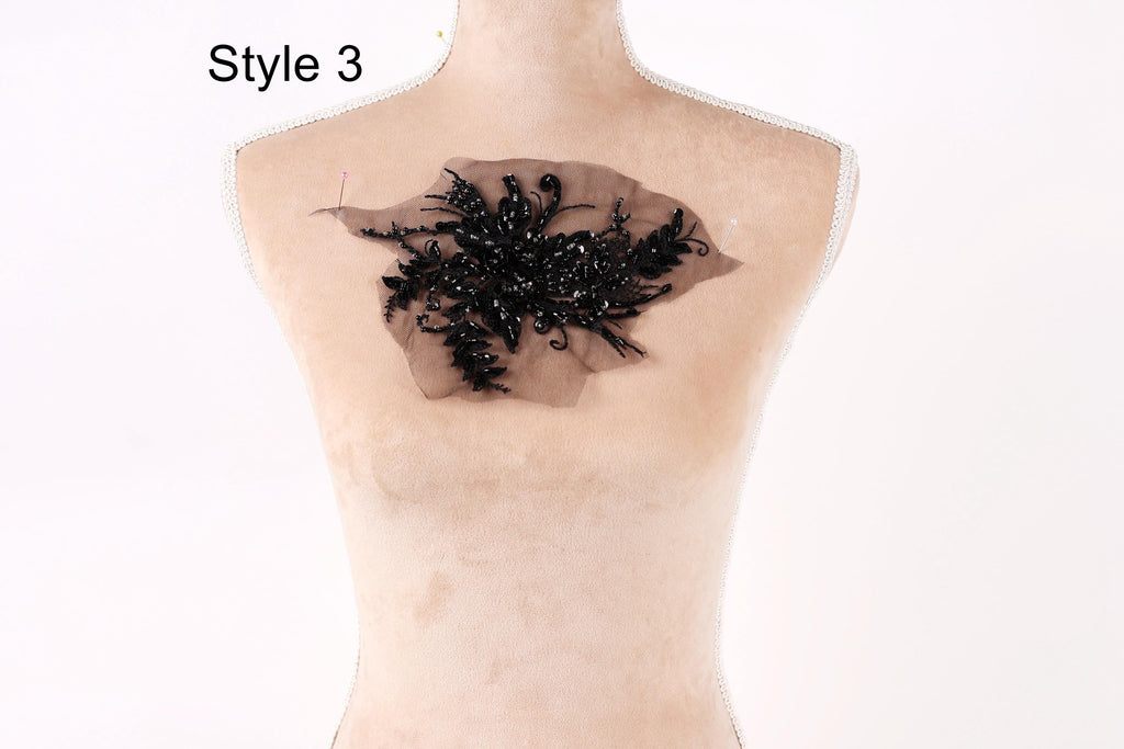 A mannequin with a black lace or beaded design on its bust, positioned against a white background.