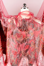 a mannequin wearing a vibrant red and pink dress with intricate beading and embroidery details.