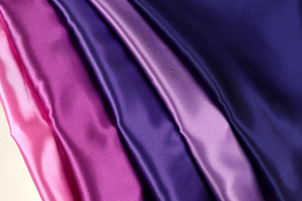 a close-up view of a fabric with a gradient of colors, transitioning from pink to purple.