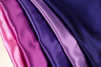 a close-up view of a fabric with a gradient of colors, transitioning from pink to purple.