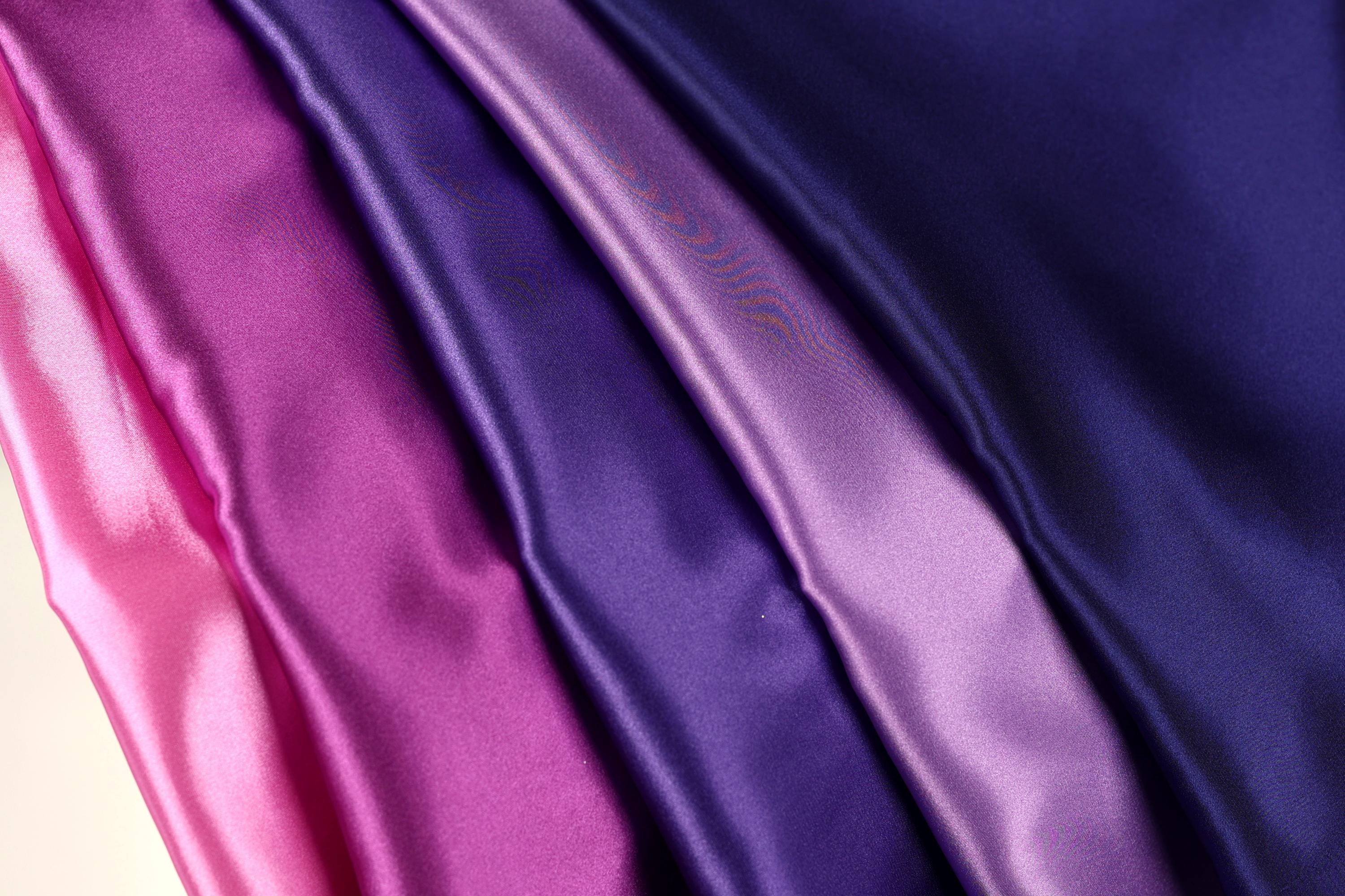 a close-up view of a fabric with a gradient of colors, transitioning from pink to purple.