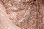 The image is a close-up of a fabric with a pink and gold sequined pattern, featuring a detailed and intricate design.