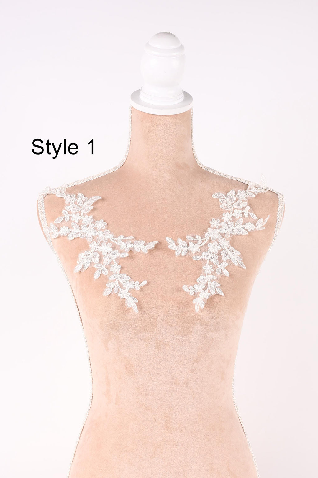 A mannequin with white lace flowers on its shoulders, displayed against a plain background.