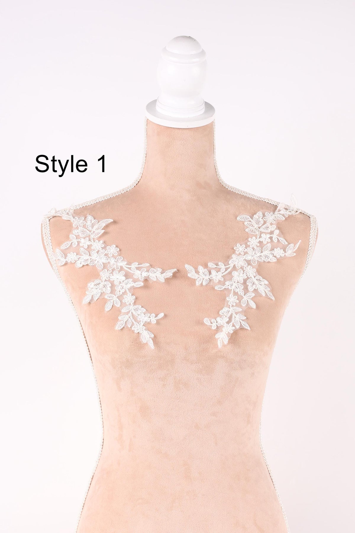 A mannequin with white lace flowers on its shoulders, displayed against a plain background.