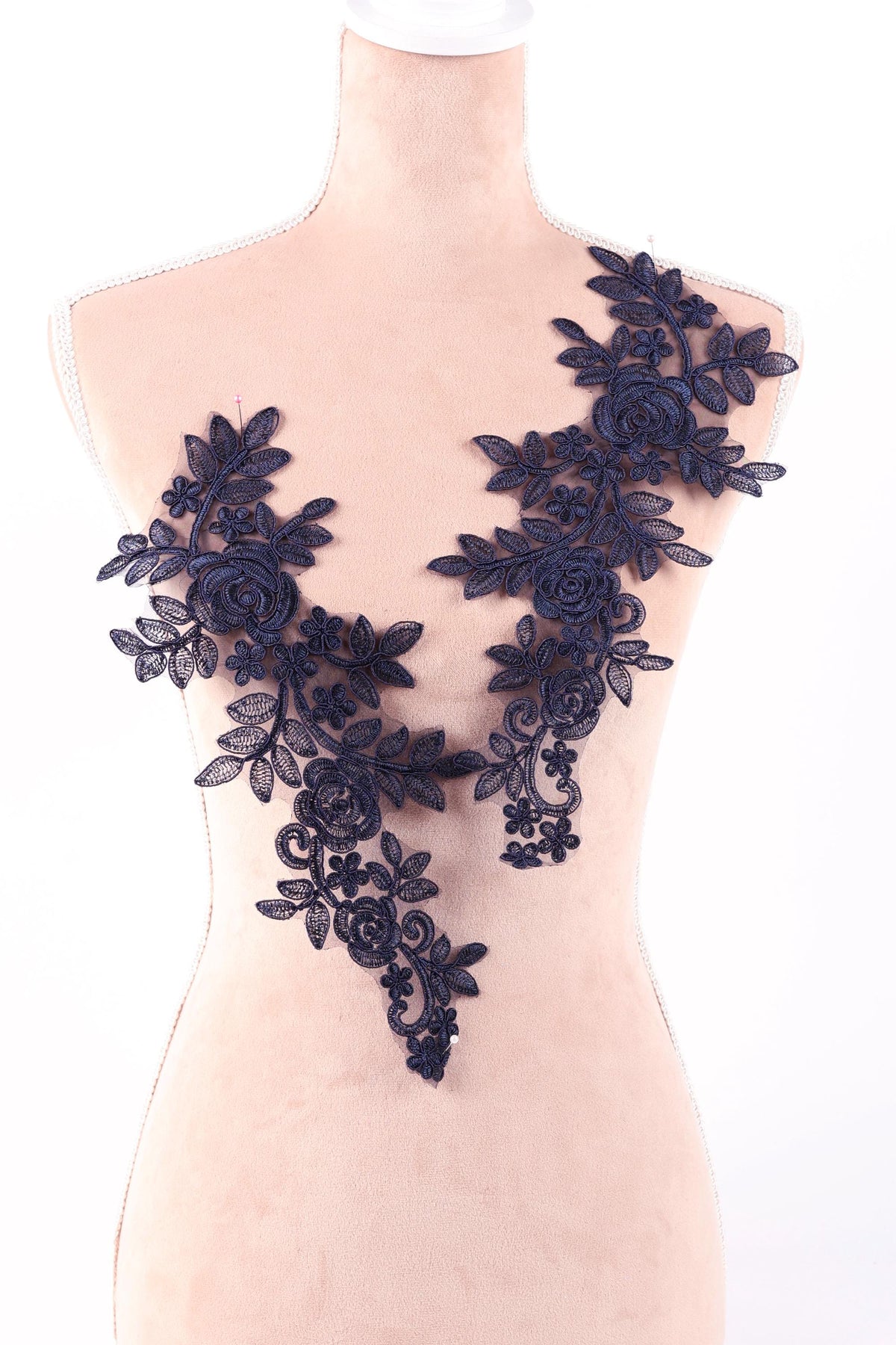 A mannequin wearing a dress with a floral lace design on the bust area.