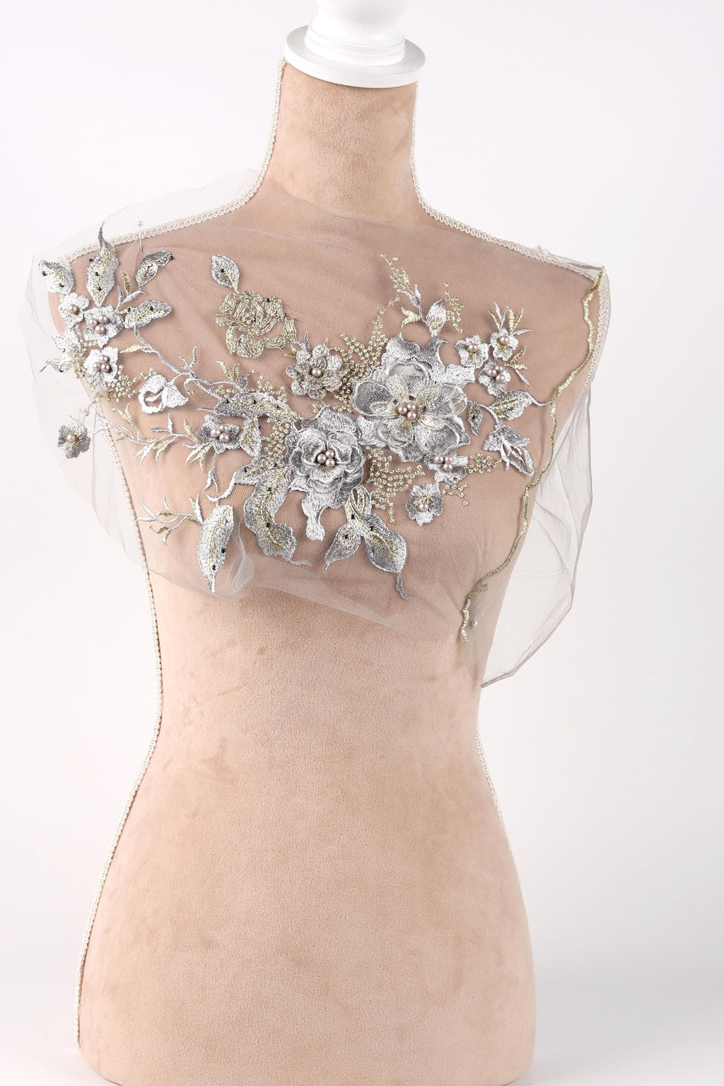 A mannequin with a sheer, floral-embellished dress or garment on display.