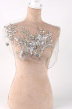 A mannequin with a sheer, floral-embellished dress or garment on display.