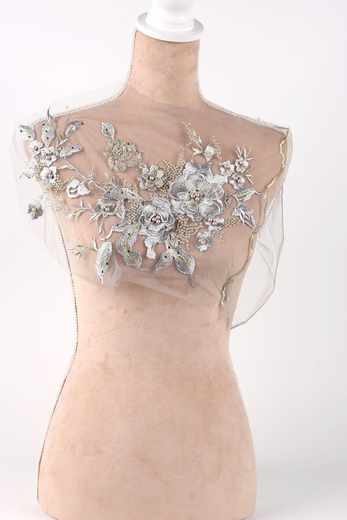 A mannequin with a sheer, floral-embellished dress or garment on display.
