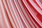 a close-up view of a fabric with a gradient of pink and red colors, creating a visually appealing and textured appearance.
