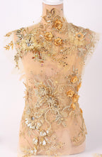 A mannequin wearing an elaborate gold and beige floral dress with intricate embroidery and embellishments.