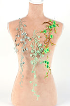 A mannequin torso with three green floral designs on it, including branches with green leaves and flowers.