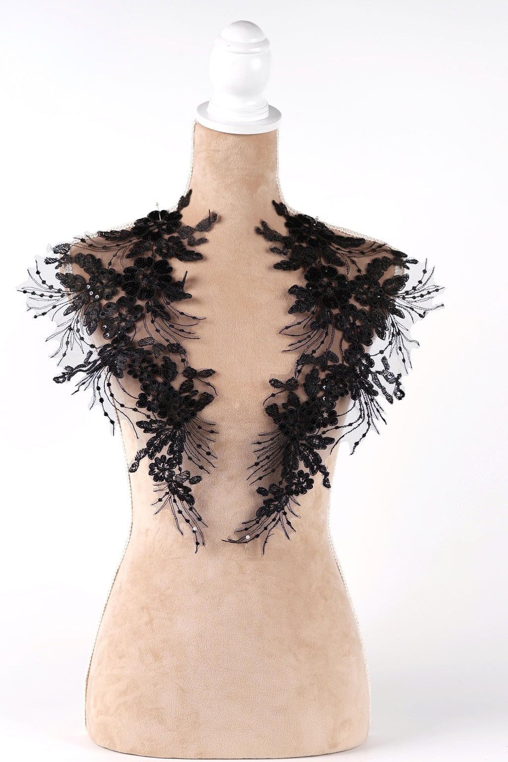 A mannequin wearing a black lace dress with intricate floral patterns.