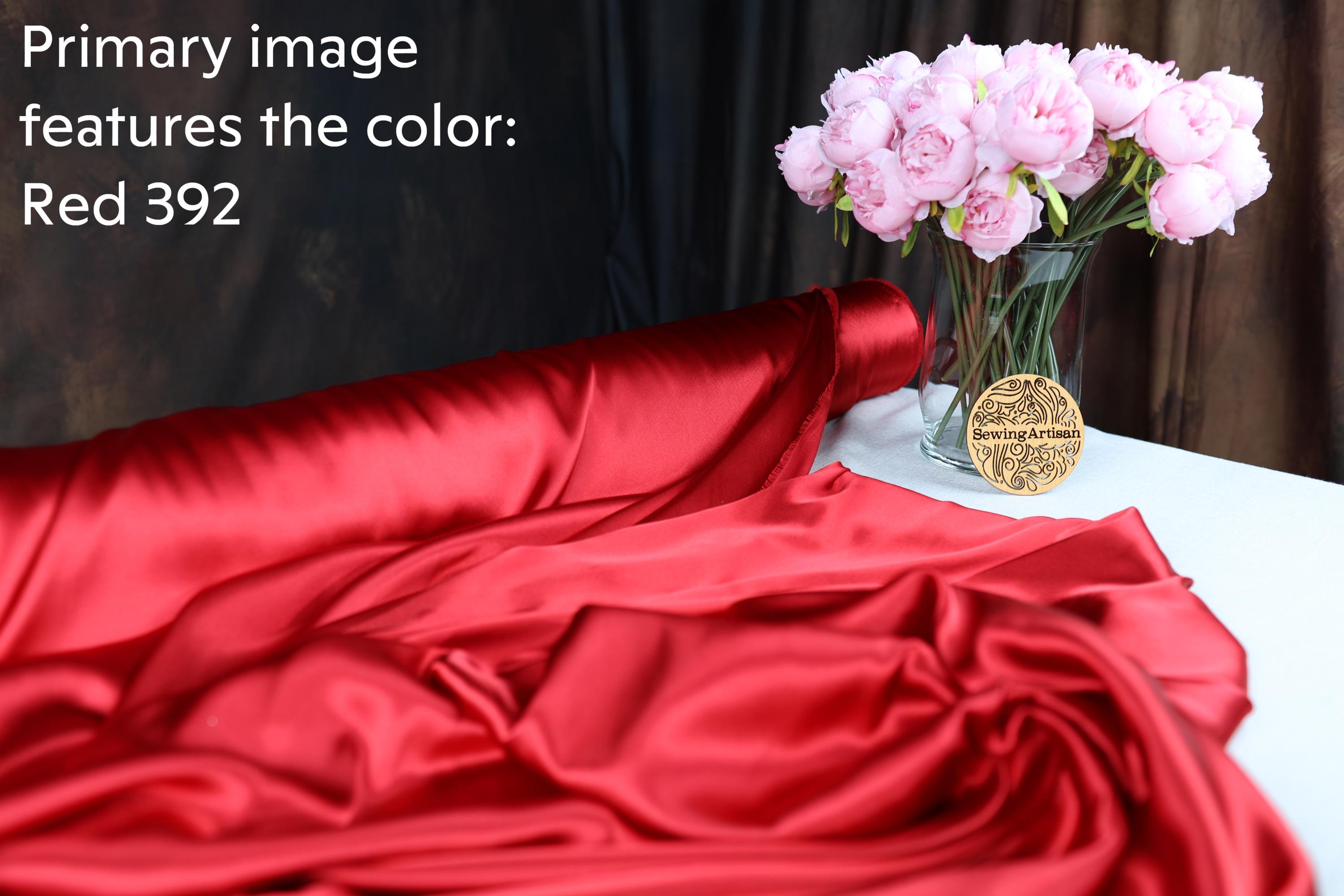 the color red, with a bouquet of pink flowers in a glass vase placed on a white tablecloth.