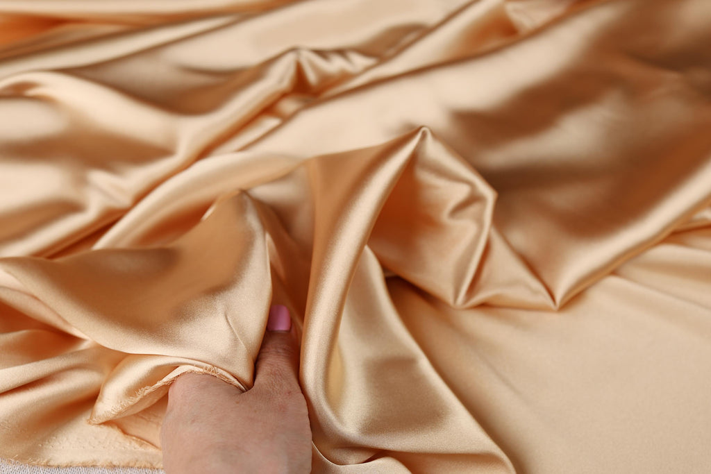 a person&#39;s hand on a satin fabric