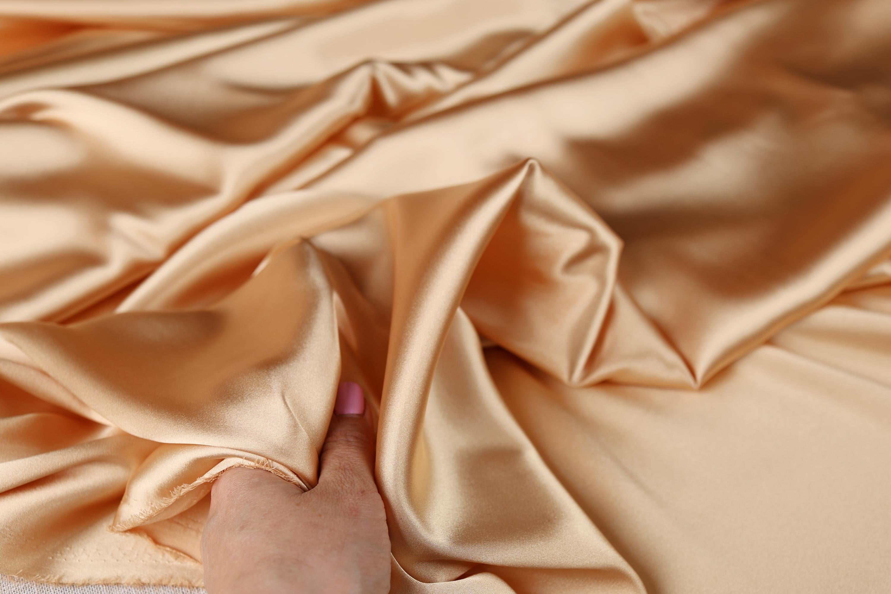 a person&#39;s hand on a satin fabric