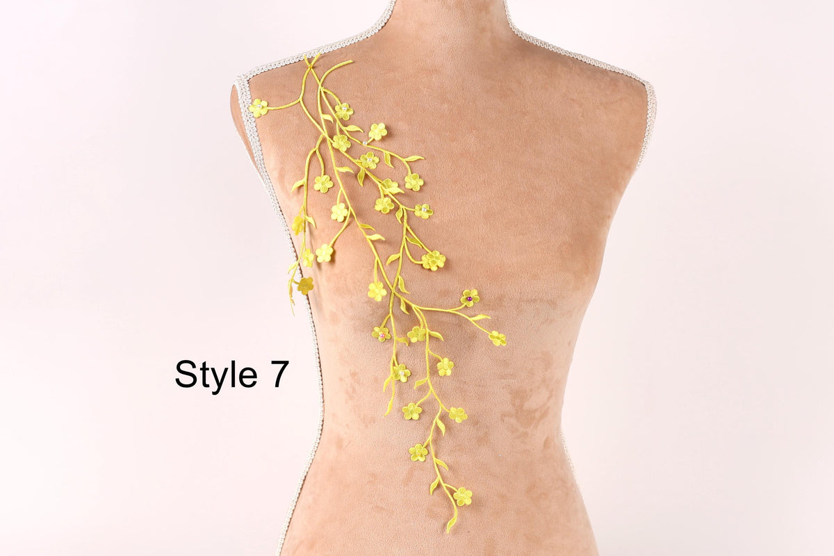 A mannequin with yellow flower-like branches hanging from its shoulder, against a plain white background.
