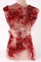 A mannequin wearing a red dress with intricate floral embroidery and lace details.