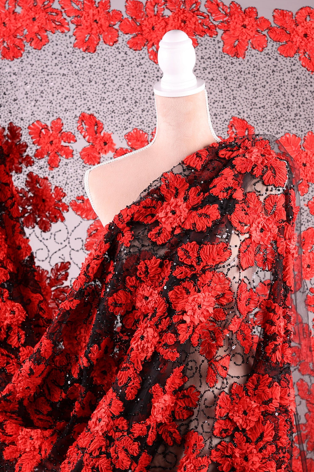 a close-up view of a fabric with a striking red floral pattern. The fabric appears to be a sheer material, with a black and red floral design that creates a visually appealing contrast. The fabric is spread out, revealing its intricate details and the vibrant colors of the red flowers.