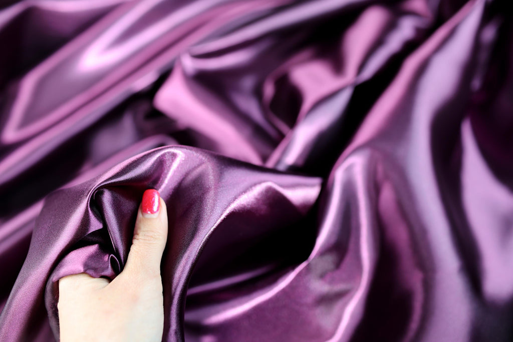 a woman's hand on a purple satin fabric