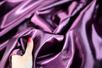 a woman's hand on a purple satin fabric