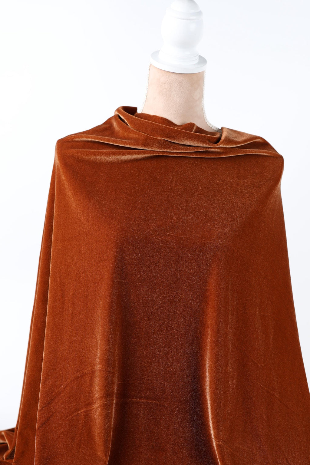 a close-up view of a piece of brown fabric, possibly velvet, with a white object attached to the end.