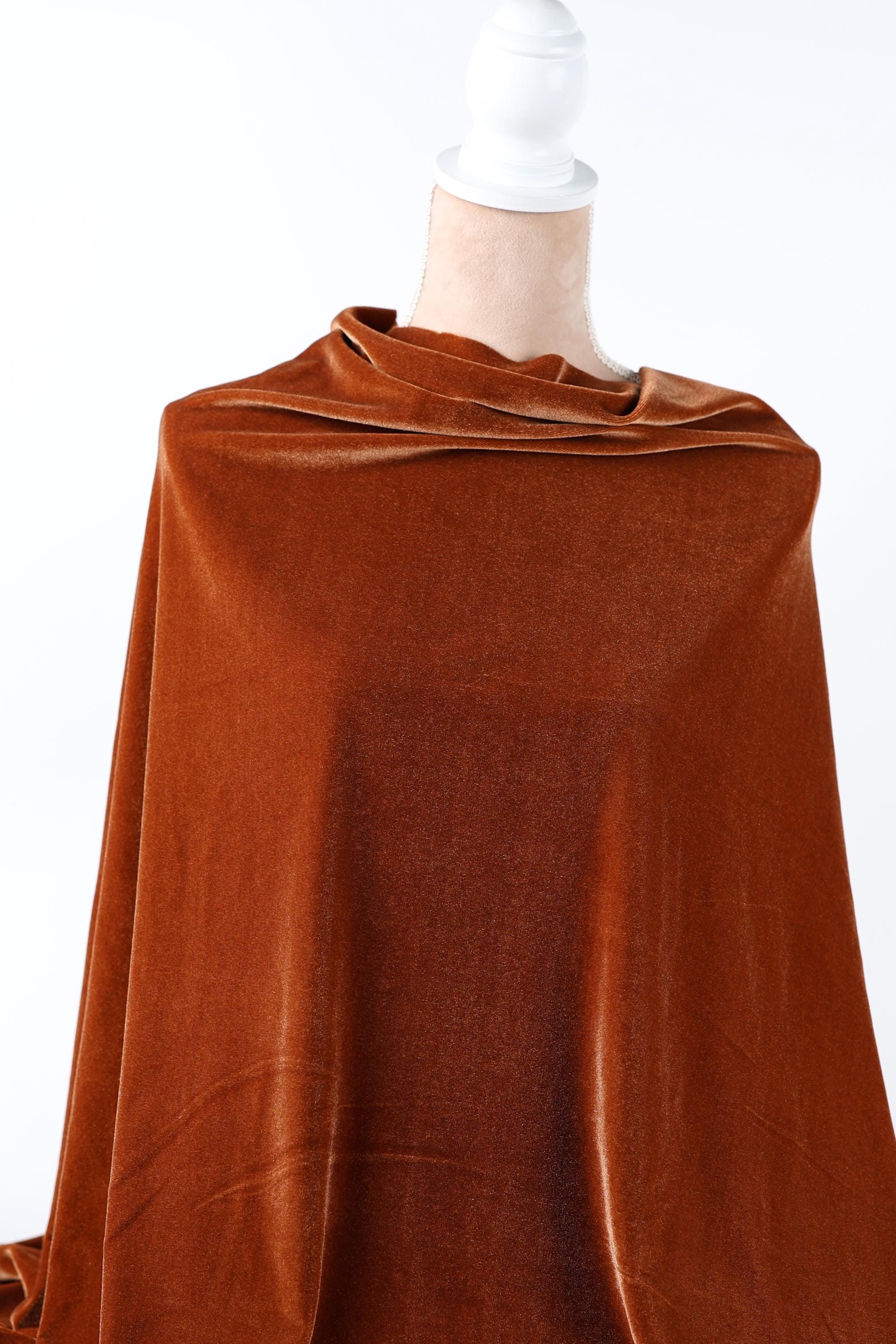 a close-up view of a piece of brown fabric, possibly velvet, with a white object attached to the end.