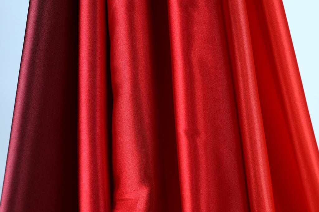 a close-up view of a red fabric, with a dark red fabric partially visible on the left side.