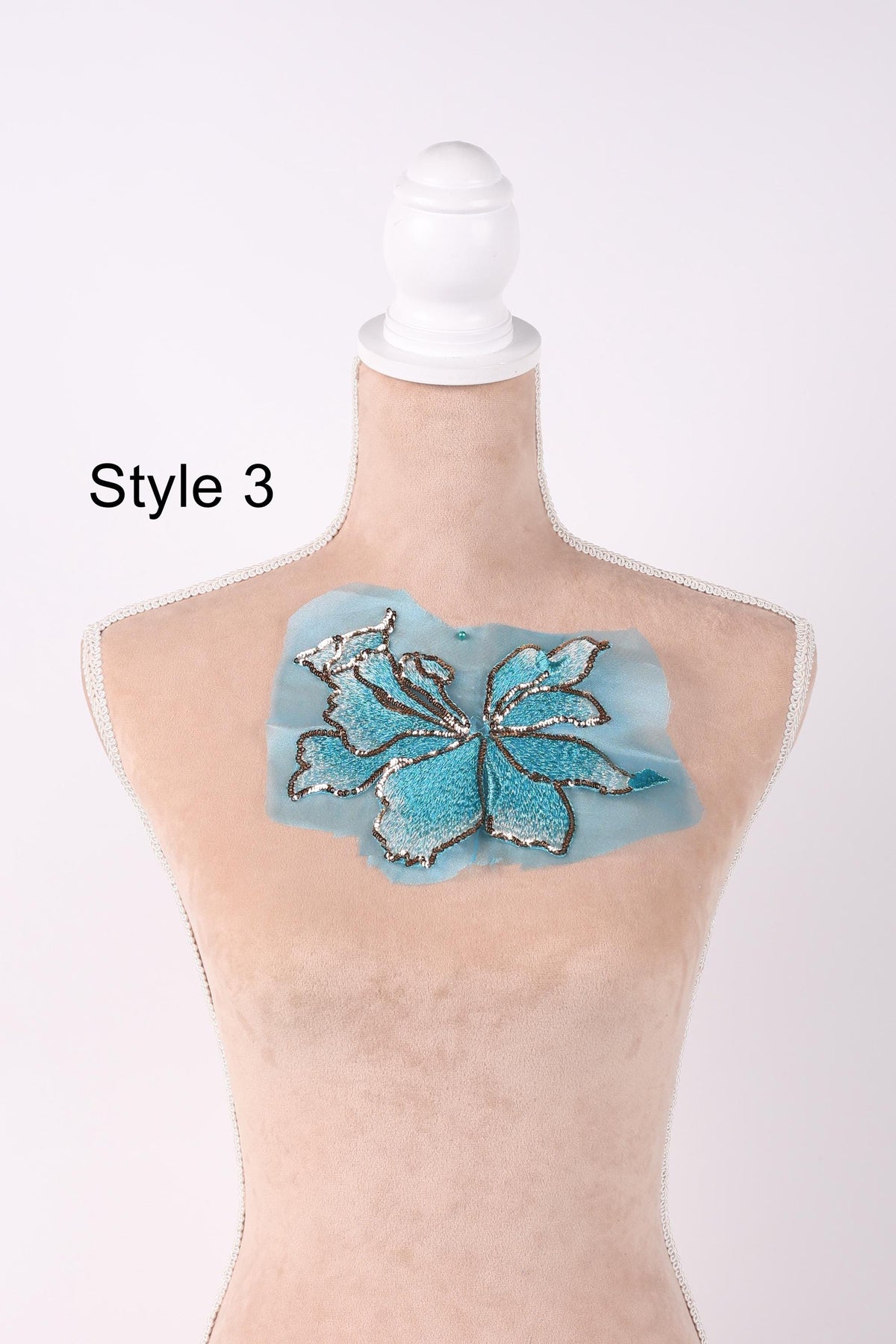 A mannequin with a blue and silver embroidered design on its chest.