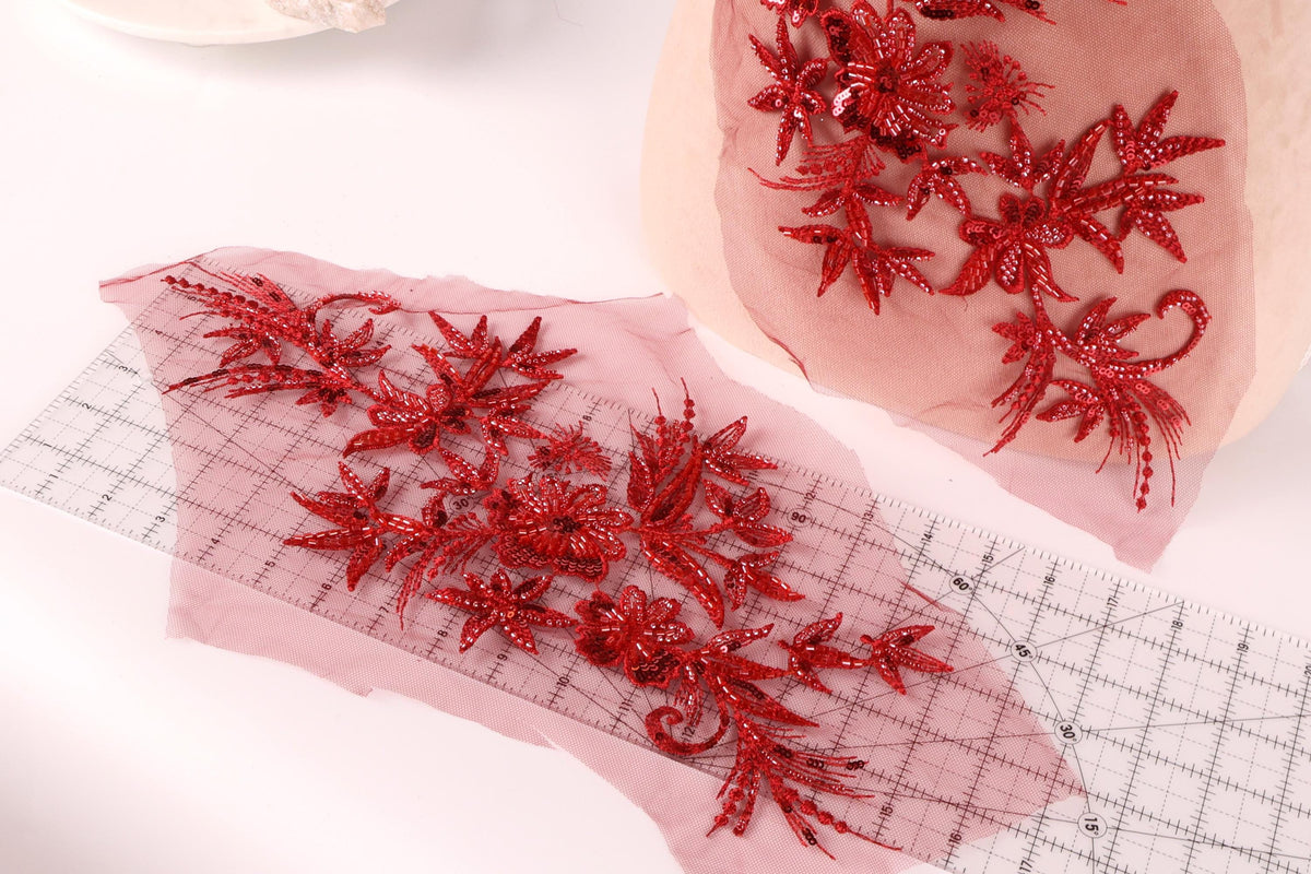 a close-up view of red sequin flowers on a pink background, with a ruler and a piece of paper with red sequin flowers on it.