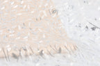 The image is a close-up of a fabric with a floral pattern, featuring a mix of white and beige colors. The fabric appears to be made of lace or a similar delicate material, with intricate white and beige embroidered designs.