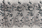 The image is a close-up of a fabric with a floral pattern, featuring a variety of blue and gray flowers and leaves.