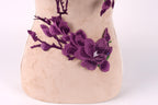 a close-up view of a beige fabric with a purple flower embroidered on it.